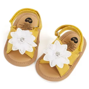 Vue détaillée de sandales jaunes pour bébé ornées de délicates fleurs en dentelle blanche.