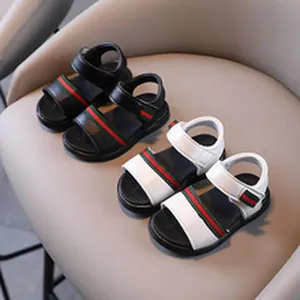 Close-up of children's leather sandals in black and white with red-green stripes