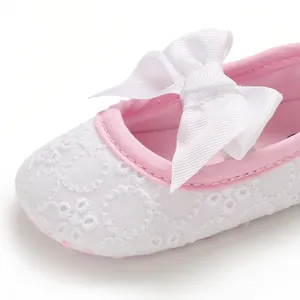 Gros plan détaillé montrant le motif en dentelle blanche et le nœud rose sur une chaussure