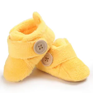Soft yellow fuzzy baby booties with large decorative wooden button