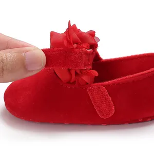 Detailansicht eines roten Baby-Prinzessinenschuhs mit Blume und Klettverschluss.