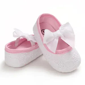 Vue détaillée de chaussures de princesse en dentelle pour bébé avec un grand nœud rose.