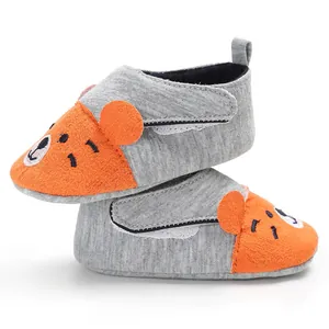 Gros plan de chaussures bébé grises et orange avec semelles souples pour nourrissons
