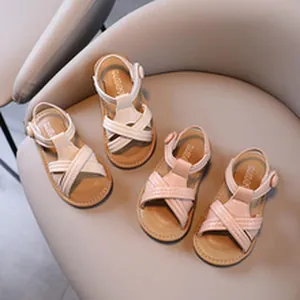 Stylish toddler girls cross-strap summer sandals in cream and pink displayed on a chair