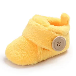 Macro detail of soft yellow plush baby walker bootie featuring a large wooden button