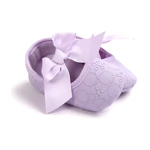 Close-up detail showing the intricate embroidery and soft ribbon bow on these purple baby shoes