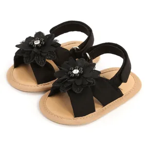 Vue détaillée de sandales noires pour bébé avec décoration florale et semelles souples