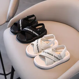 Macro view of black and white kids' casual sandals with cross-straps on a grey chair