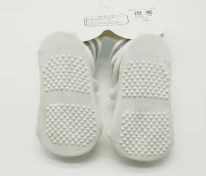 Detail of white newborn baby socks featuring anti-slip silicone dots on the soles