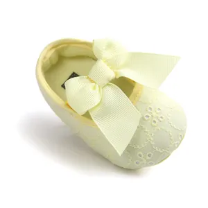 Close-up of yellow embroidered baby princess shoe with large ribbon bow detail