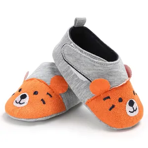 Détail de chaussures de marche pour bébé à semelle souple avec un joli visage d'ours.