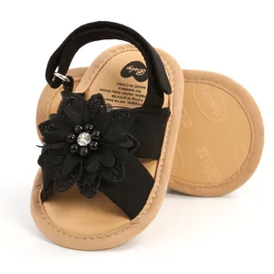 Vue détaillée de sandales noires pour bébé avec fleur décorative et perle.