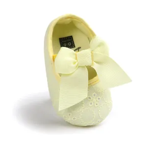 Detail of yellow embroidered baby girl princess shoe with large ribbon bow