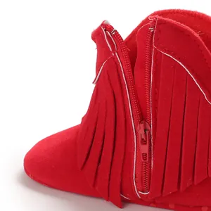 Close-up detail of red baby bootie showing the zipper and soft fringe decoration.