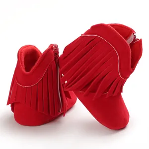 Close-up of baby red fringe boots with side zipper and soft suede texture.