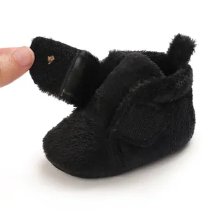 Close-up detail of soft black plush baby walking shoe featuring an adjustable velcro strap