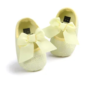 Macro view of pale yellow embroidered baby shoes with large decorative bow