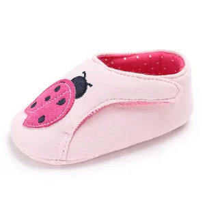 Gros plan de chaussure de marche bébé rose avec broderie coccinelle et doublure à pois