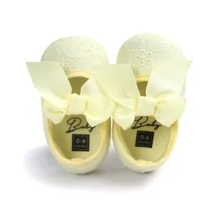 Close-up of yellow embroidered baby princess shoes with large ribbon bows