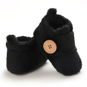 Detailed close-up of black fuzzy baby shoes featuring a large decorative wooden button