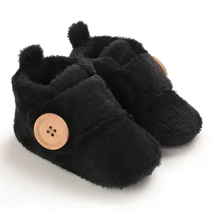 Close-up detail of soft black fuzzy baby winter boots with decorative wooden button.