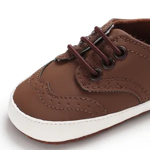 Detailopname van bruine babyloopschoenen met brogue-details en elastische veters voor baby's