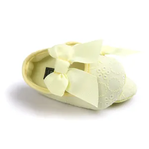 Close-up of yellow embroidered baby princess shoe with a large soft ribbon bow