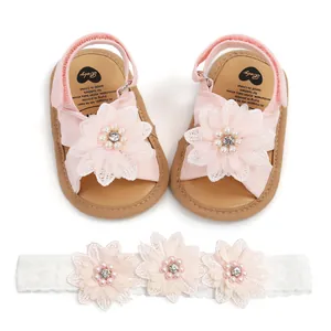 Gros plan de sandales roses pour bébé avec perles et bandeau assorti en dentelle blanche.