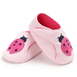 Détail de chaussures bébé roses à semelle souple avec motif coccinelle brodé mignon