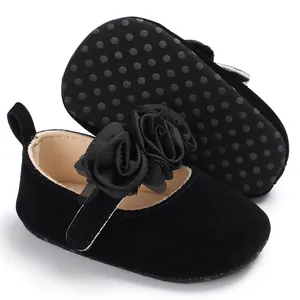 Nahaufnahme schwarzer Baby-Prinzessinenschuhe aus Samt mit Stoffrosen und Rutschsohle