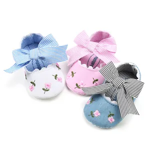 Detail of baby princess shoes with floral embroidery and large striped bows in three colors
