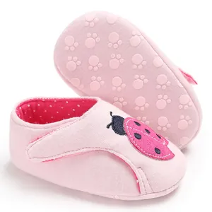 Détail de chaussures bébé roses avec broderie coccinelle et semelle souple antidérapante