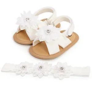 Détail de sandales blanches pour bébé avec fleurs et bandeau en perles assorti