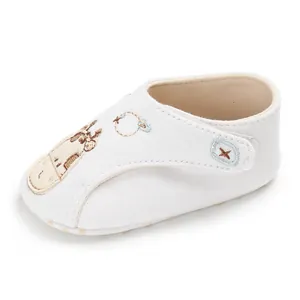 Gros plan d'une chaussure de bébé blanche en coton avec une broderie girafe mignonne