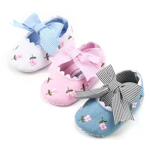 Close-up detail of floral embroidered baby girl shoes with elegant striped bows