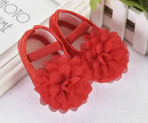 Detail von roten Babyschuhen für Mädchen mit großer Chiffonblume und Gummiband.