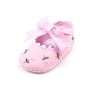 Detailed view of pink baby princess shoe with floral embroidery and large striped bow.