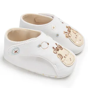 Détail de chaussures blanches pour bébé avec broderie girafe et semelle en tissu souple