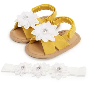 Gros plan sur les sandales jaunes pour bébé et le bandeau avec fleurs en dentelle