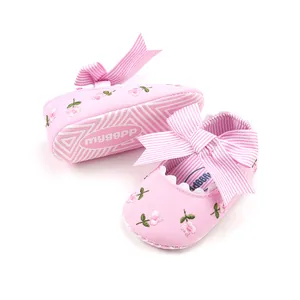 Detailed close-up of pink infant princess shoes with floral embroidery and striped bow.