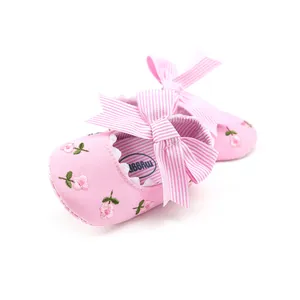 Detailed view of pink baby princess shoes with floral embroidery and a striped bow