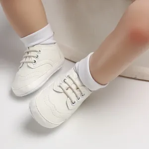 Detailopname van witte baby-loopschoenen met een zachte zool en antislipontwerp.