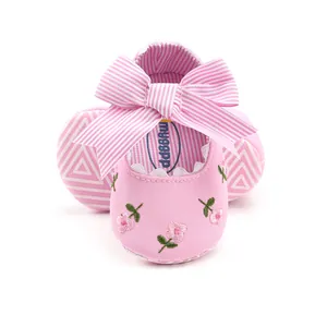 Detail of pink baby walking shoes with floral embroidery and striped bow decoration