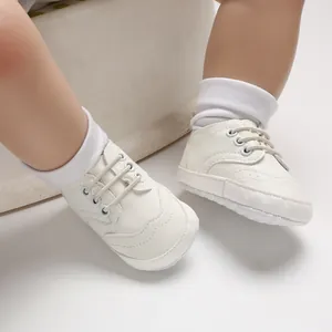 Close-up van witte babyschoenen met zachte zool gedragen met witte sokjes.