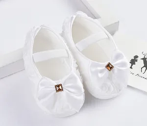 Nahaufnahme eleganter weißer Baby-Prinzessin-Lauflernschuhe mit Schleife und Blumen
