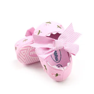 Detailed view of pink embroidered baby princess shoes with a large striped bow design