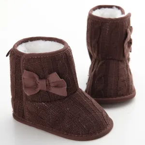 Details von braunen Strick-Babystiefeln mit Schleife und Kunstfellfutter.