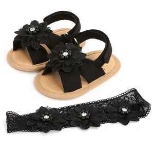 Détail de sandales noires pour bébé avec fleurs et bandeau en dentelle assorti