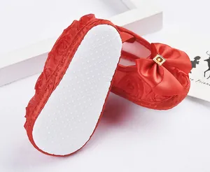 Nahaufnahme roter Baby-Lauflernschuhe mit weißer rutschfester Sohle und elegantem Schleifendetail