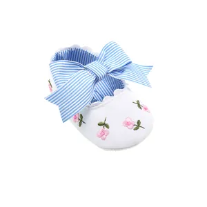 Detail view of baby princess shoe with pink floral embroidery and blue striped bow.